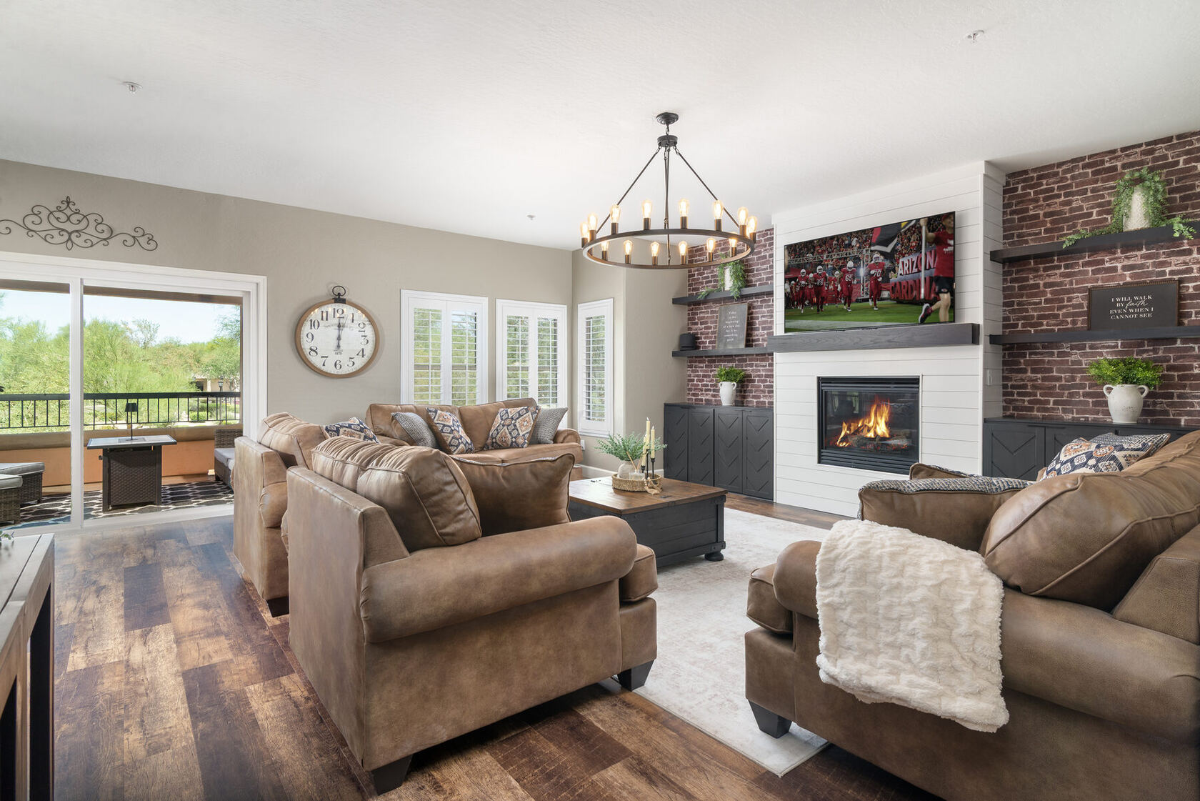 Living room with cognac leather seating, brick accent wall, and fireplace