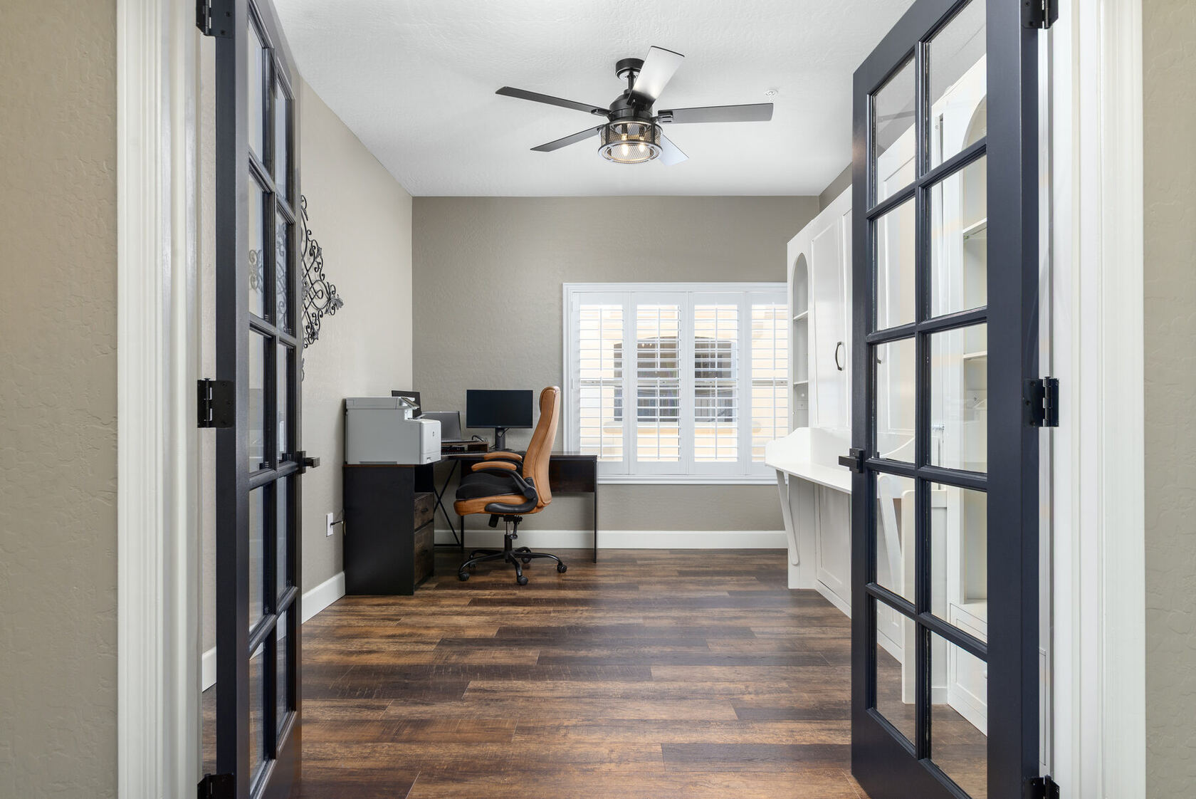 Private office with desk seen through black-framed French doors